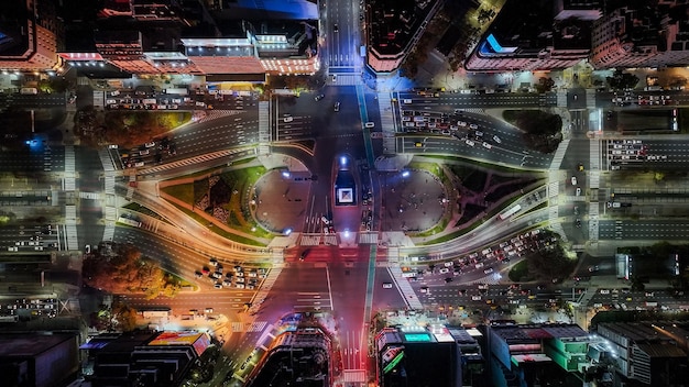 A street intersection in a Brazilian city with smart traffic lights, displaying real-time traffic information. Electric buses are waiting at a charging station nearby. The image should reflect a blend of technology and urban planning to reduce traffic congestion.