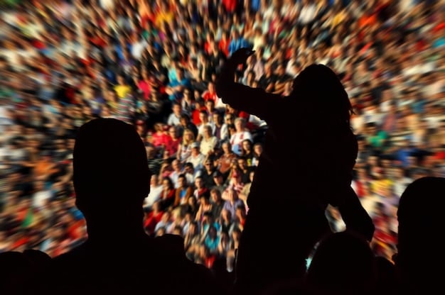 A split image showing the contrast between a pre-pandemic crowded concert and a present-day socially distanced outdoor gathering, with people wearing masks and maintaining a safe distance. The image should illustrate the shift in how cultural events are experienced.