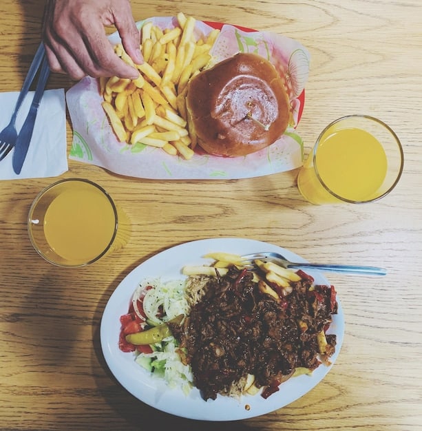 A collage showing traditional Brazilian foods like feijoada and acarajé alongside globalized fast food like burgers and fries, illustrating the cultural shift.