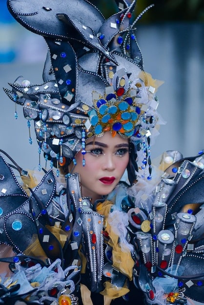 A detailed photograph showing a close-up of a Carnival costume being designed with a digital interface. The designer is using software to visualize the design in 3D and adjust the details of the costume using a stylus pen on a tablet. The scene emphasizes the blend of traditional craftsmanship with modern technology.