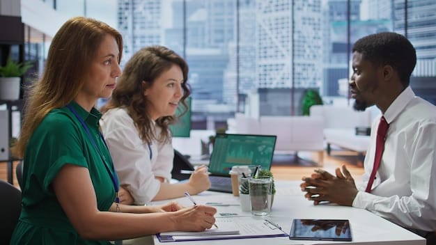 A diverse team of professionals collaborating in a modern office setting, reviewing data on laptops and discussing strategies related to ESG implementation.
