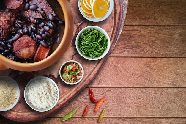 An overhead shot of a table laden with a variety of Brazilian dishes, including feijoada, moqueca, pão de queijo, and brigadeiros, showcasing the diverse flavors and vibrant colors of Brazilian cuisine, with traditional serving dishes and utensils.